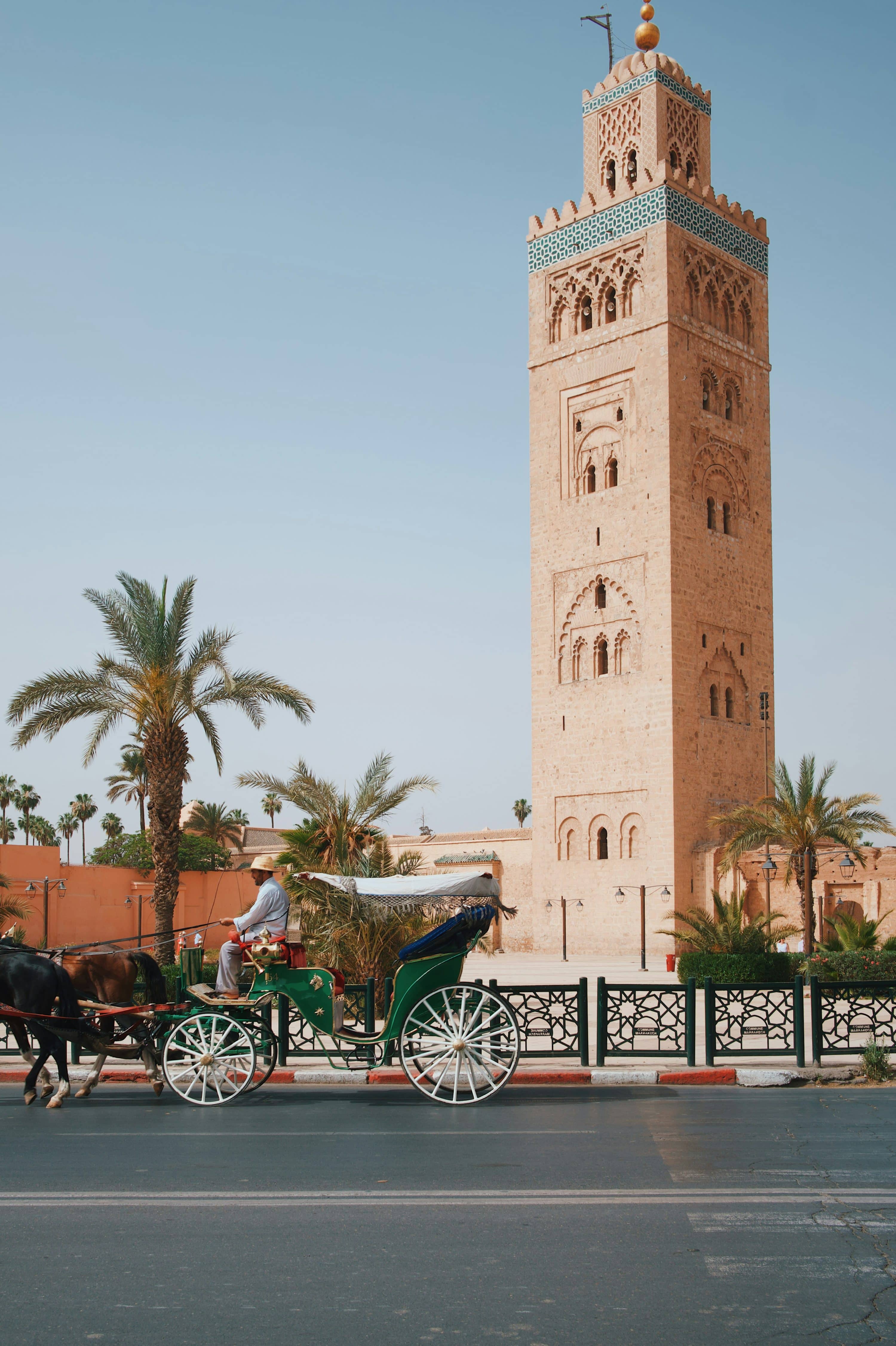 Historic Marrakech tower with a horse-drawn carriage in front